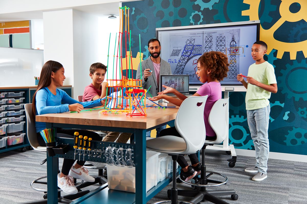 Students engaging in a creative STEM project with a SMART board in the background, showcasing interactive learning.