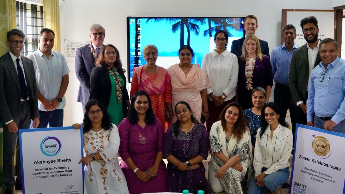 Team of SMART Technologies executives and partners at a relaunch event in India, with SMART interactive displays in the background.