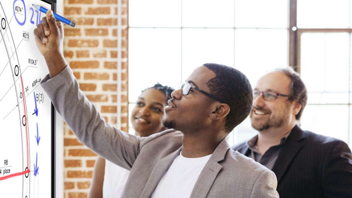 Three professionals engaging in collaborative work on a SMART interactive display.
