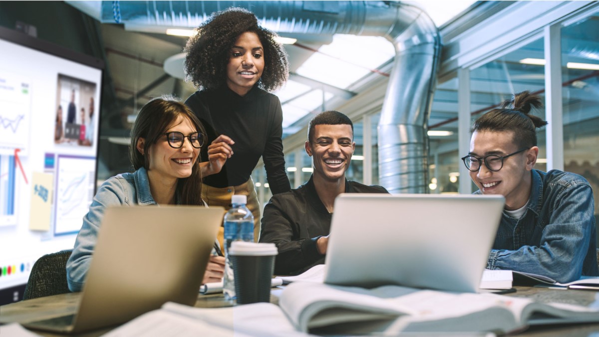 Four professionals gathered in a boardroom, laughing and collaborating in a meeting.