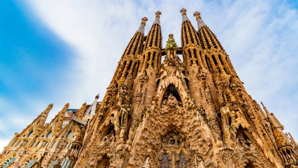 The magnificent Sagrada Família cathedral in Barcelona, showcasing its intricate spires and gothic architecture under a clear sky.