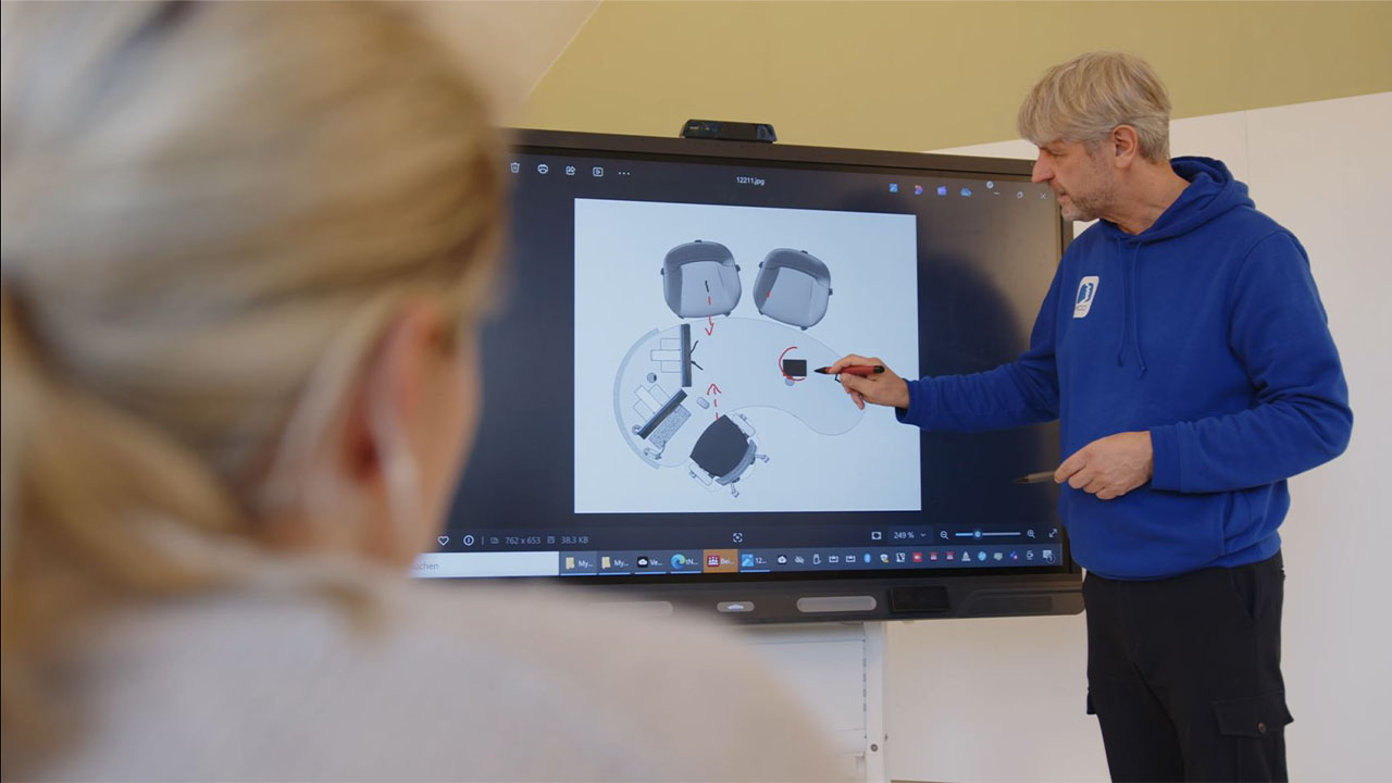 Close-up of a professional presenting detailed product schematics on a SMART Board to a focused audience.