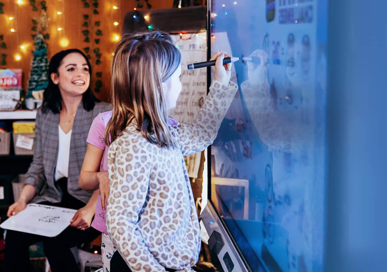 Student inking on a SMART Board with a teacher smiling