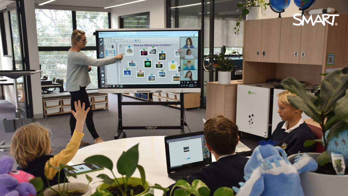 Classroom scene with teacher using a SMART Board to display multimedia content for student engagement.