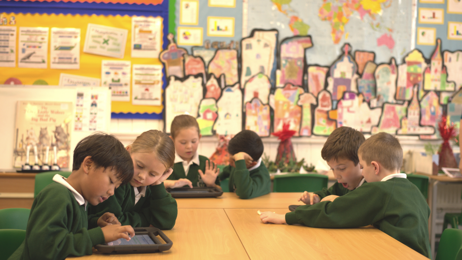 A group of students working in pairs on classroom tablets.