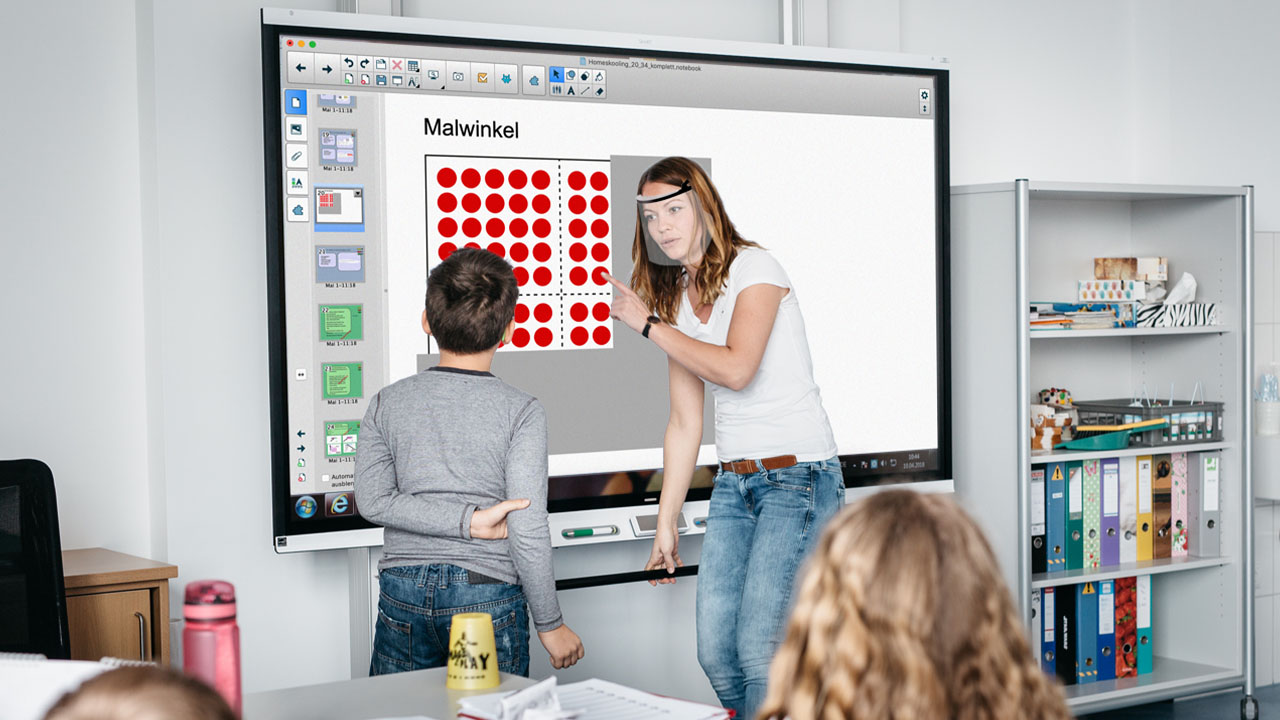Teacher guiding a student on a SMART Board displaying a math activity titled 'Malwinkel' with visual patterns of red dots.