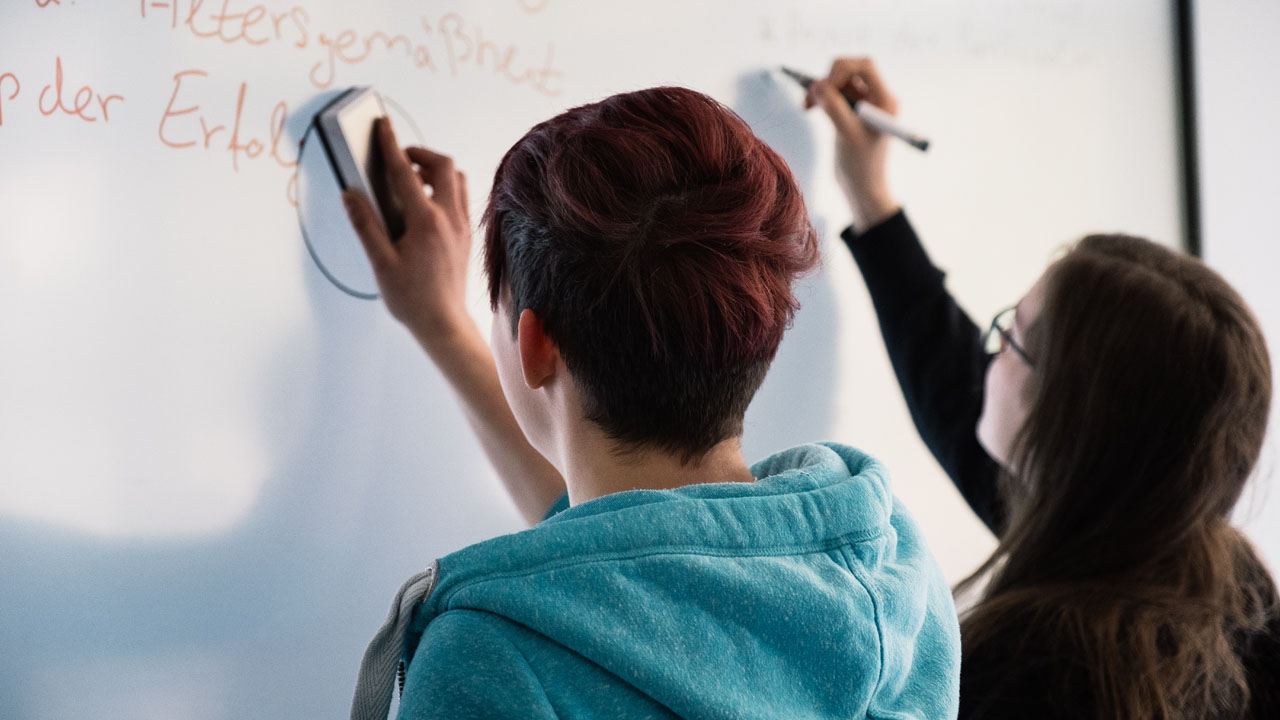 Two students collaborating on a SMART Board during a classroom activity.