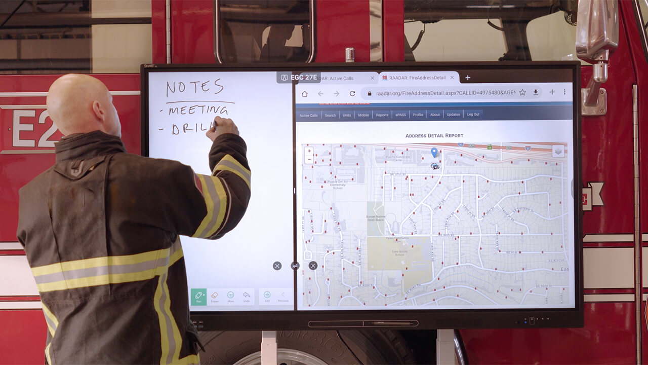 Fire department personnel using a SMART interactive display to review maps, notes, and emergency response information.