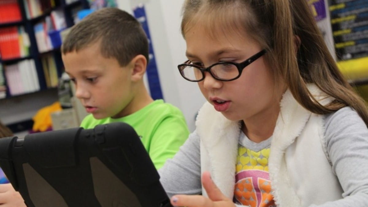 Two students working independently on tablets.