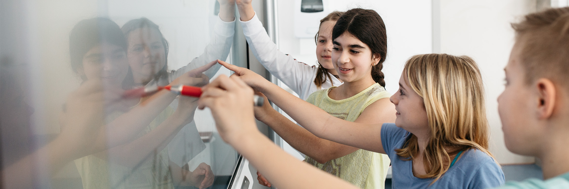 Four students annotating on a SMART board for education at once.