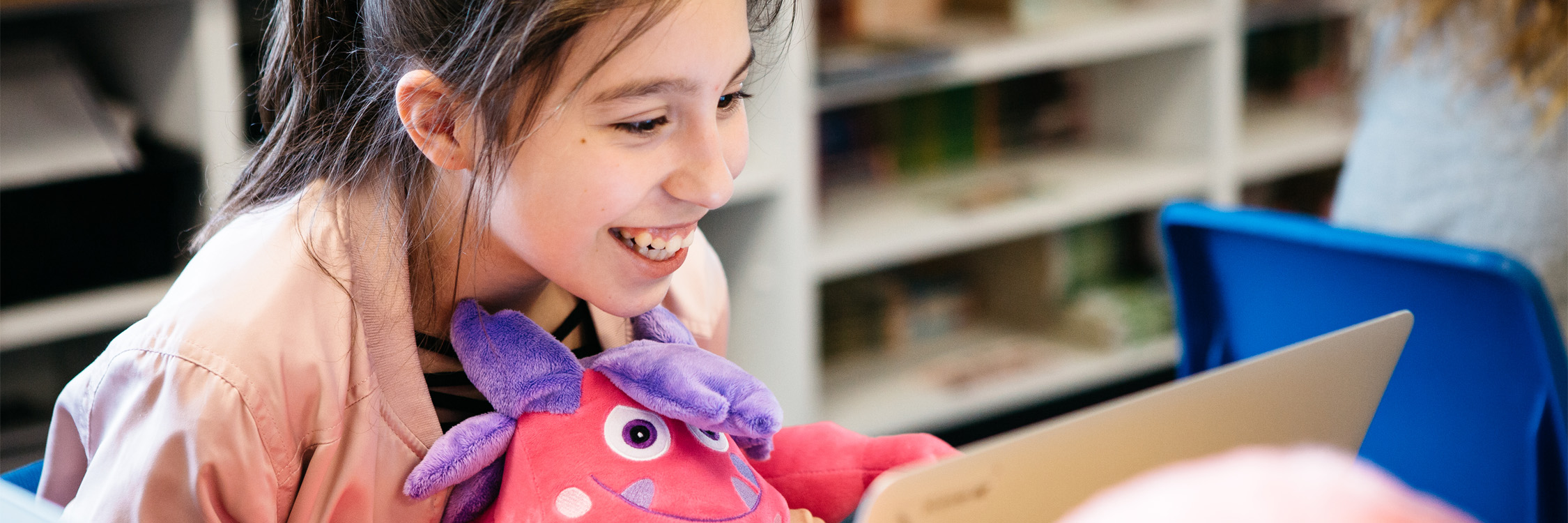 Female student with a SMART monster in hand, engaged in online learning.