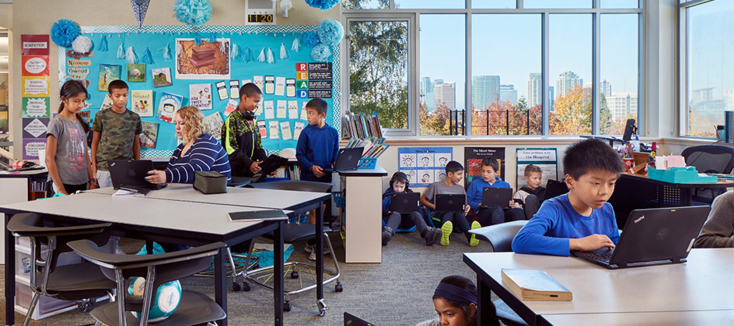 Students working independantly at different work stations throughout a colourful classroom