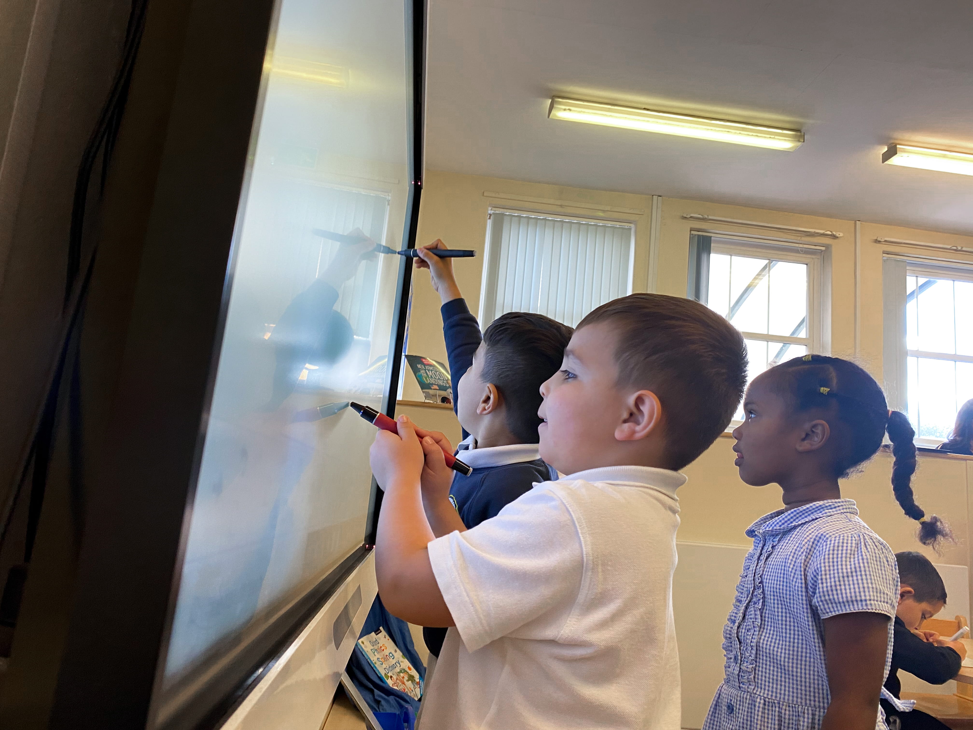 Elementary students participate in a game-based activity at the classroom SMART board.