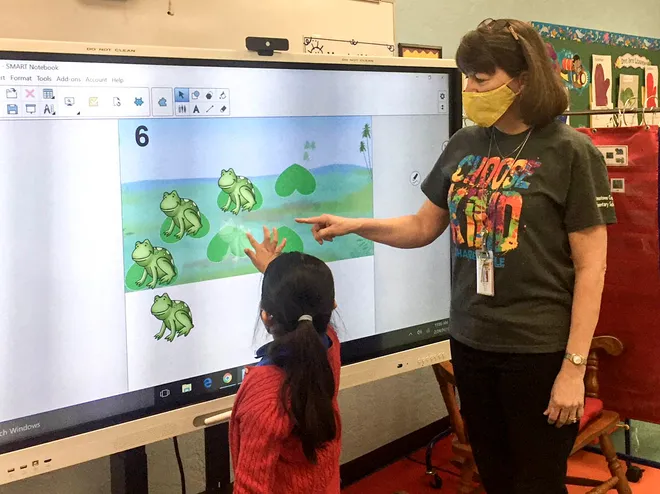 A student and teacher collaborate at a SMART board in the Palm Beach School district.