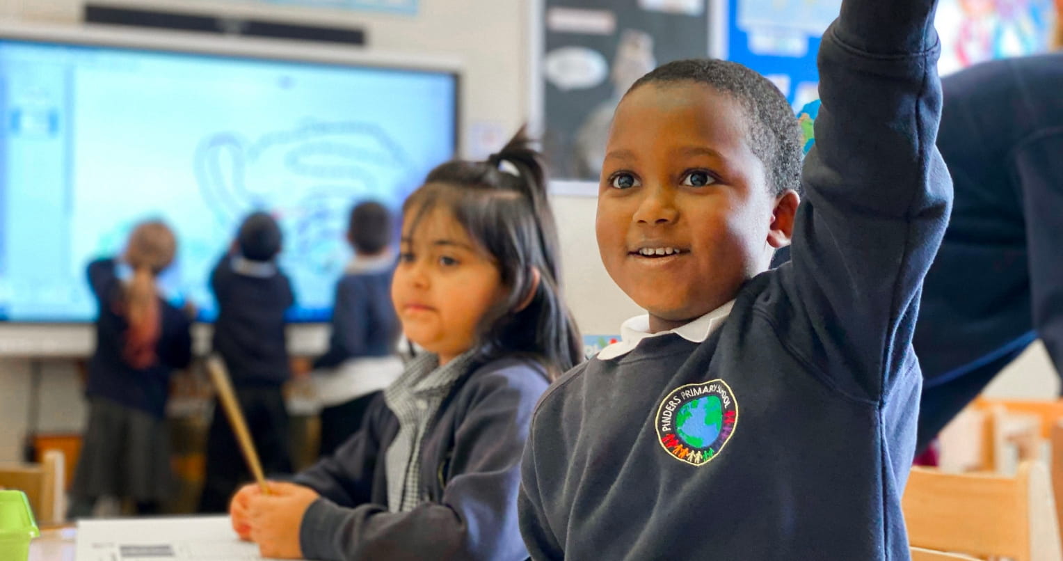Young boy student raising hand in class.