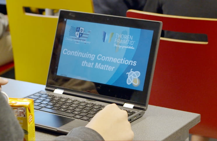 A laptop displaying a slide with the text "Continuing Connections that Matter" during a classroom presentation.