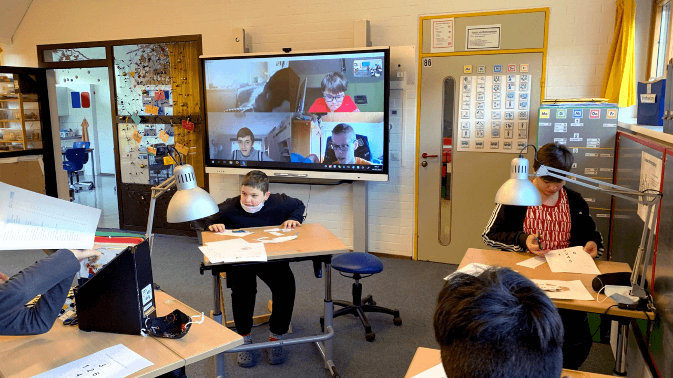 Students connecting in-person and virtually in a classroom using a SMART Board.