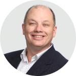 Headshot of Rick English smiling in a suit with a light background.
