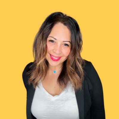Tisha Poncio smiling in a professional headshot, wearing a black blazer and white shirt against a yellow background.