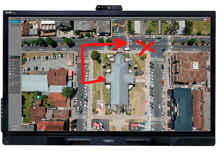 An aerial view of a neighborhood displayed on a SMART Board QX Pro, annotated with red arrows and an 'X' to highlight directions.